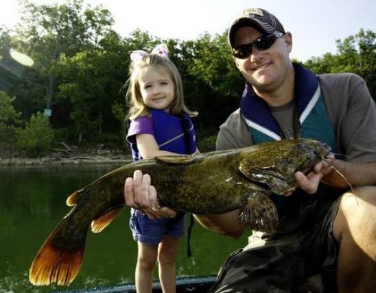Little girl and man holding up catfish.